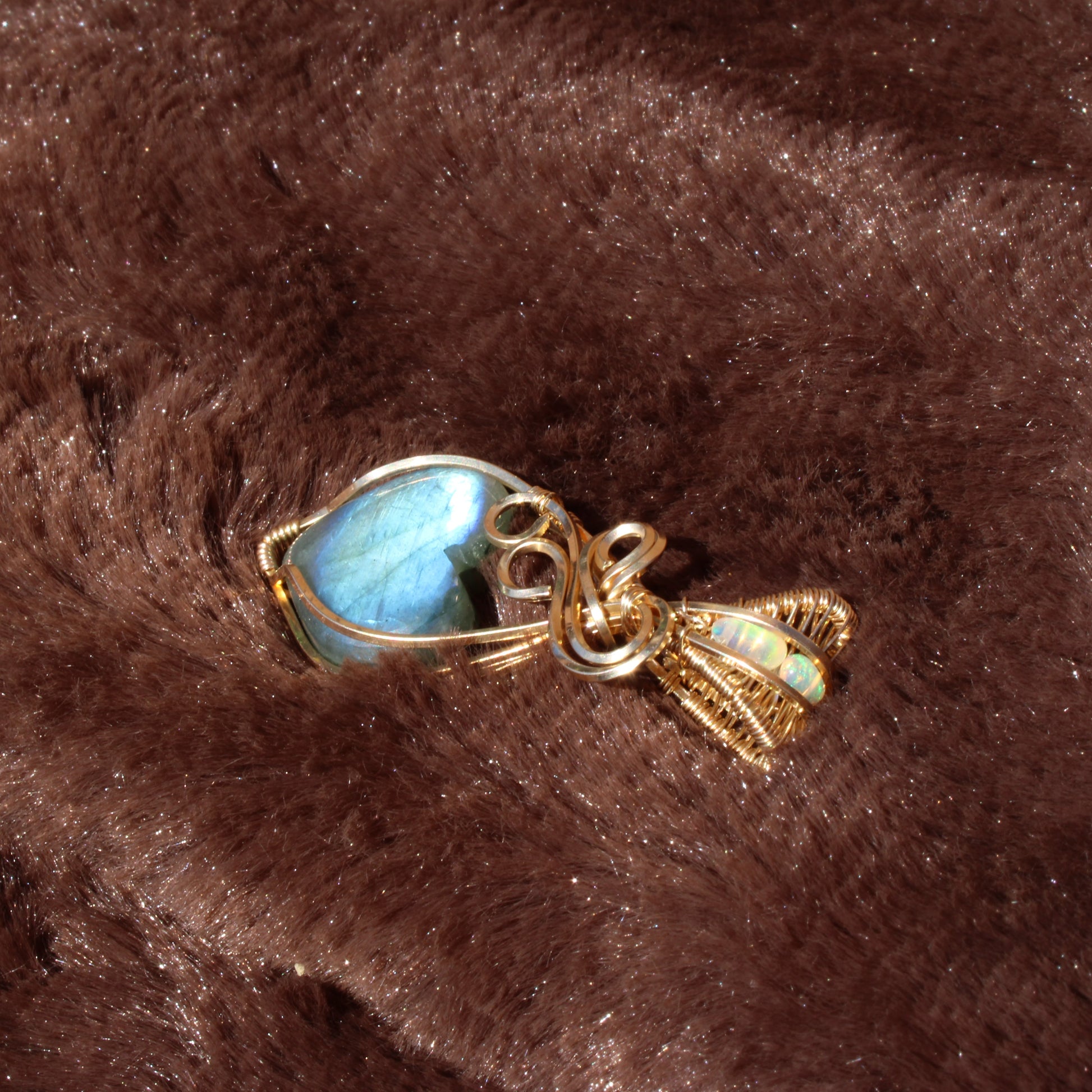 Blue flash labradorite heart pendant elegantly wrapped in gold wire, showcasing its unique shimmer
