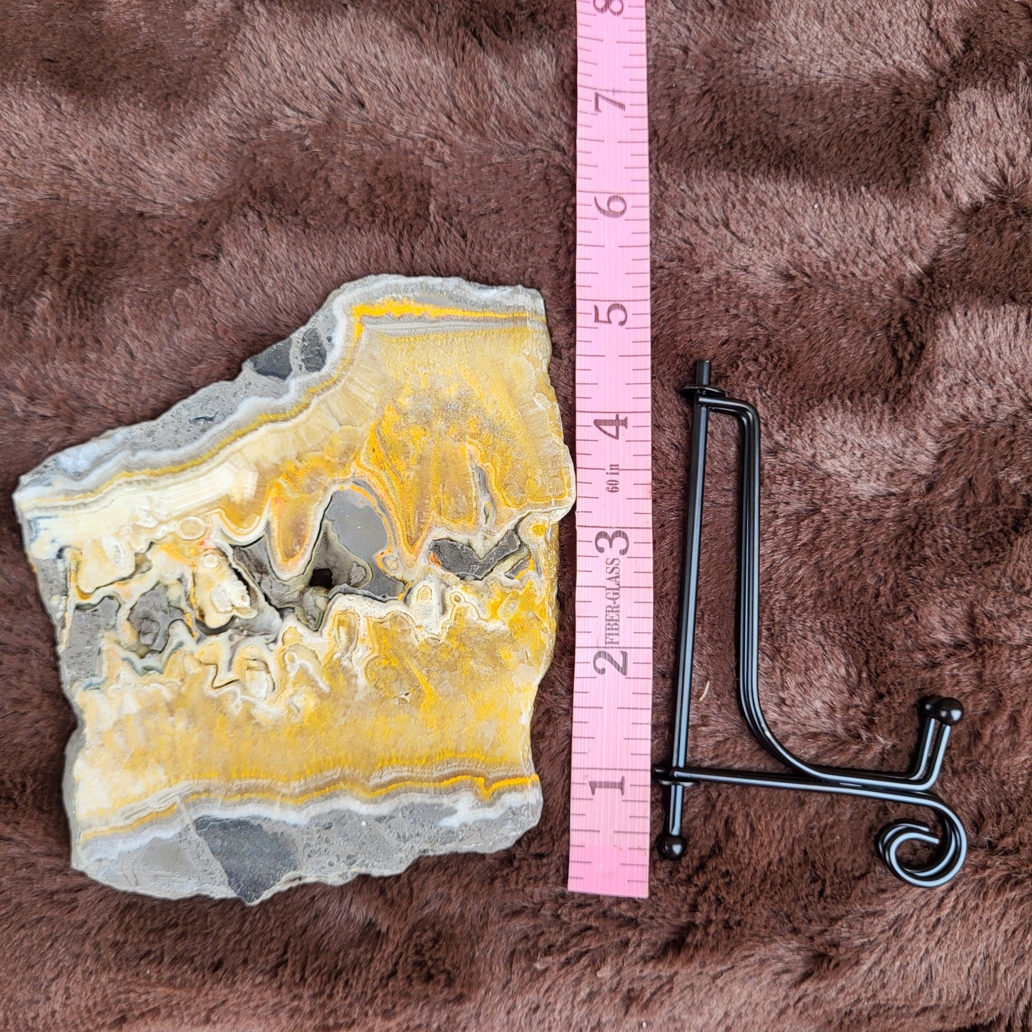 Bumblebee Jasper Slabs displayed with a measuring tape for size reference and a black display stand