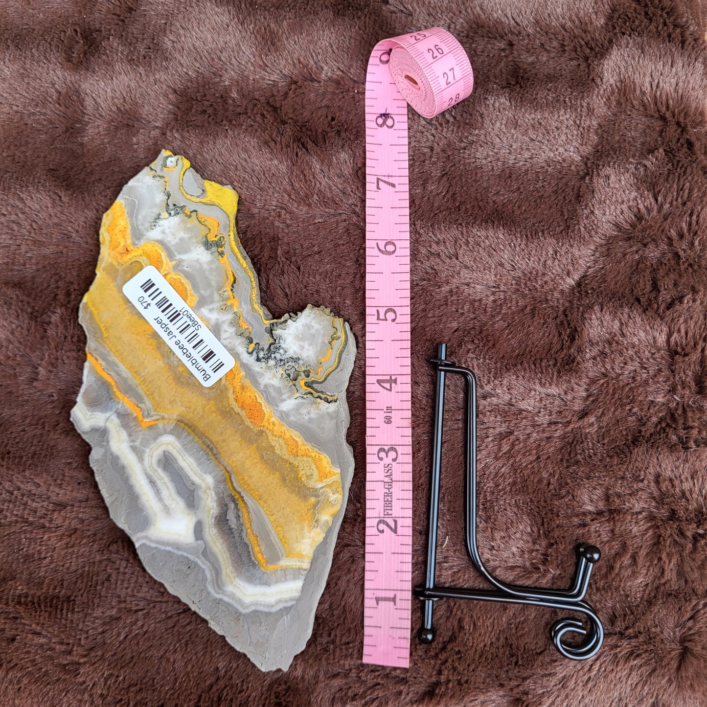 Bumblebee Jasper Slabs with Rich Yellow and Gray Patterns Next to a Measuring Tape and Stand