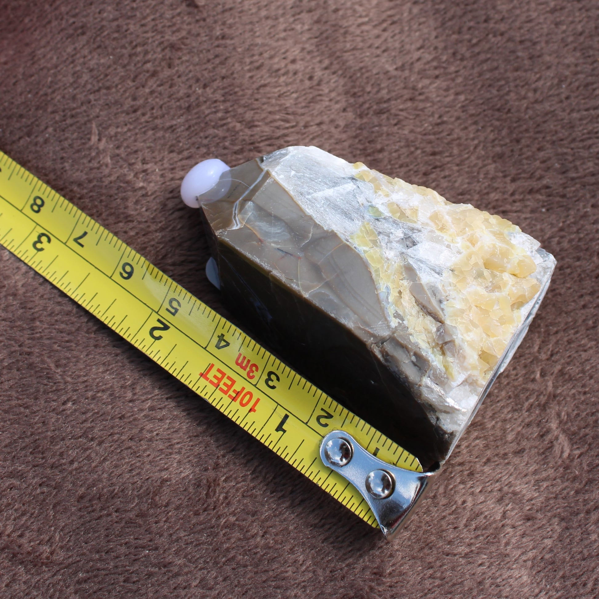 Calcite Tower crystal measuring about 3 inches from Different Branches LLC on a brown surface