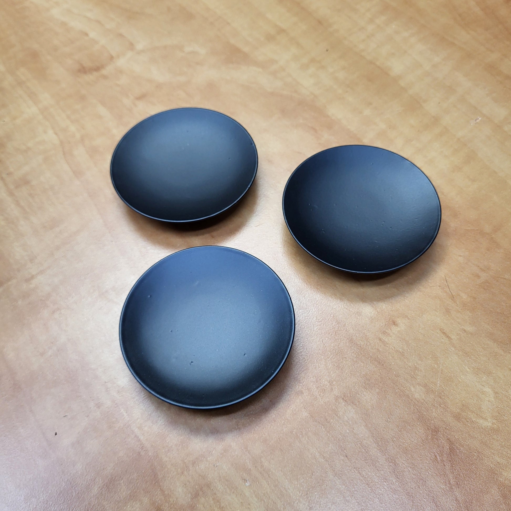 Set of three black candle dishes designed for stylish candle display and protection