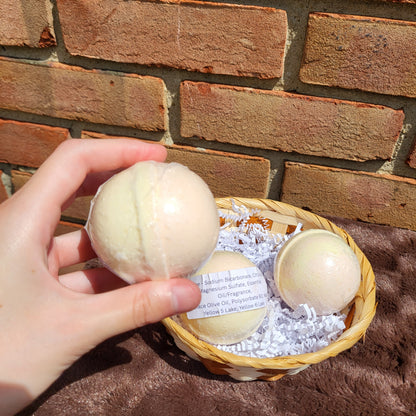 Hand holding a Citrine Bath Bomb among a basket of natural bath products against a brick background