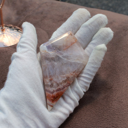 Hand holding a polished Crazy Lace Agate Diamond crystal with white and reddish brown patterns