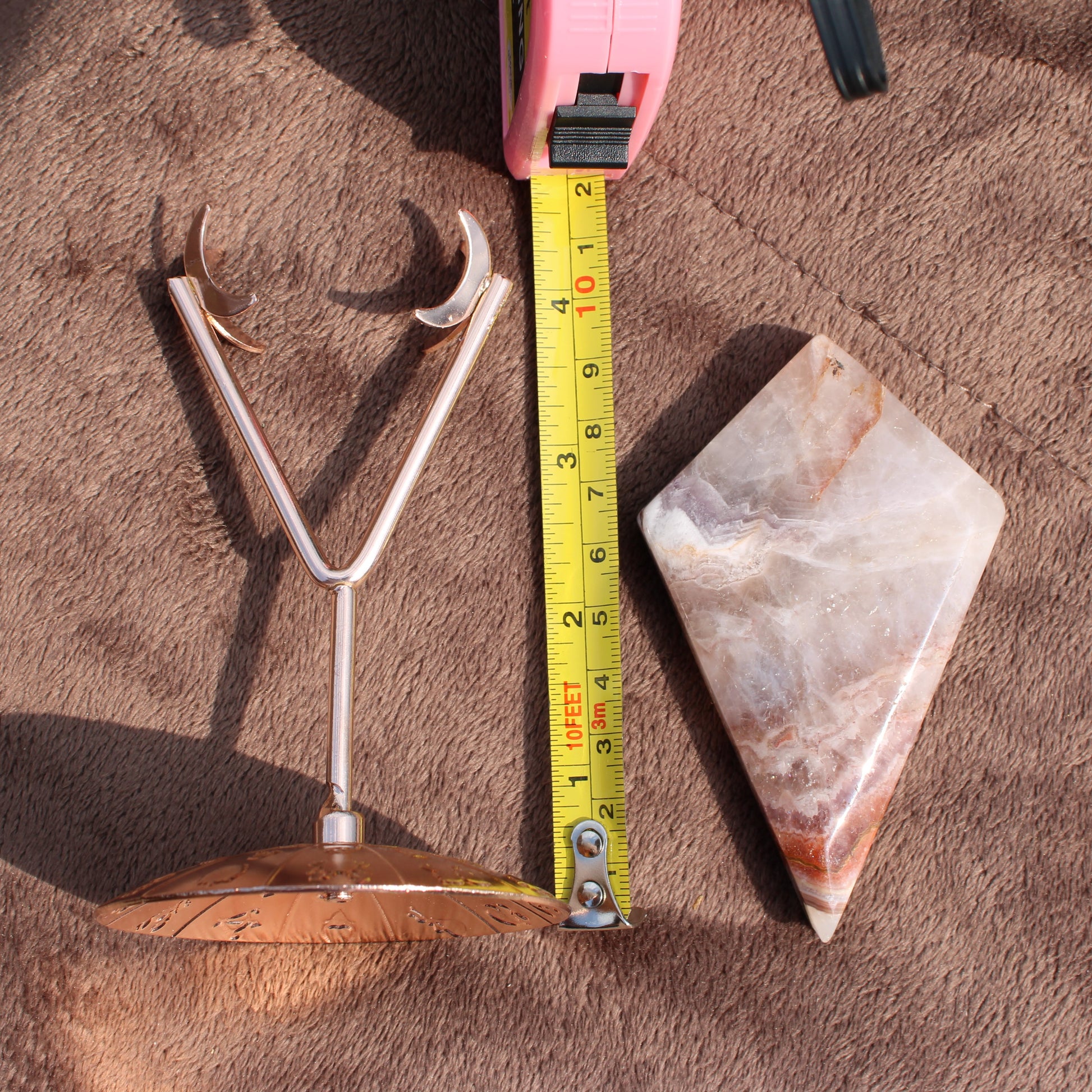 Crazy Lace Agate Diamond crystal with metal stand and measuring tape on brown fabric surface