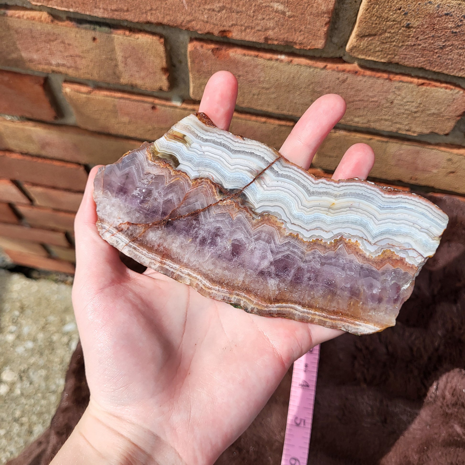 Handholding a Crazy lace amethyst slab showcasing unique patterns and natural beauty in Richfield Ohio