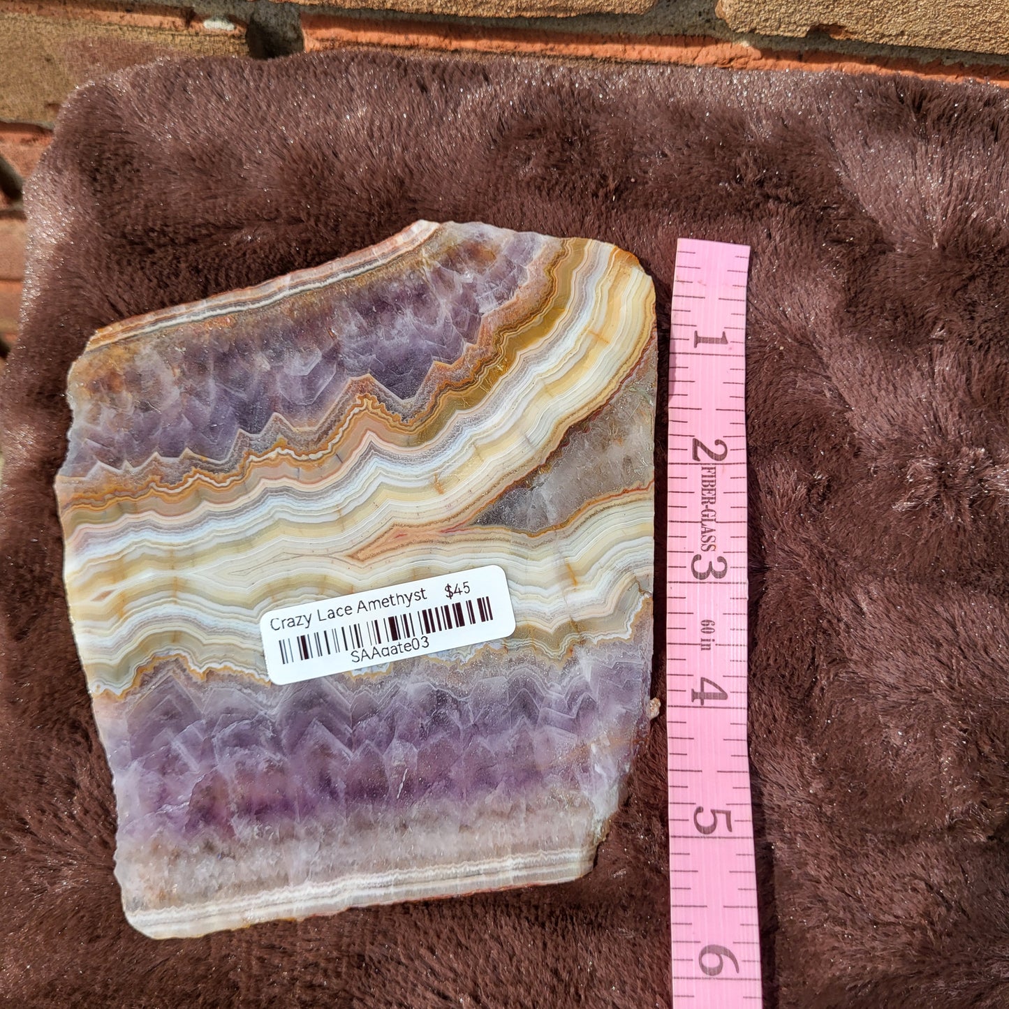 Crazy lace amethyst slab displayed on a soft surface with a measuring ruler for size reference