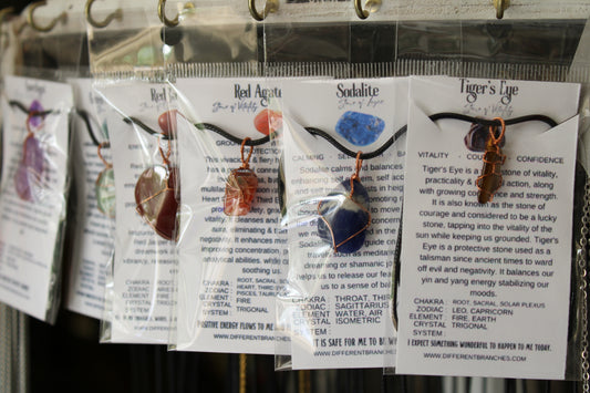 Crystal necklaces with info cards displaying various gemstones like Red Agate and Sodalite