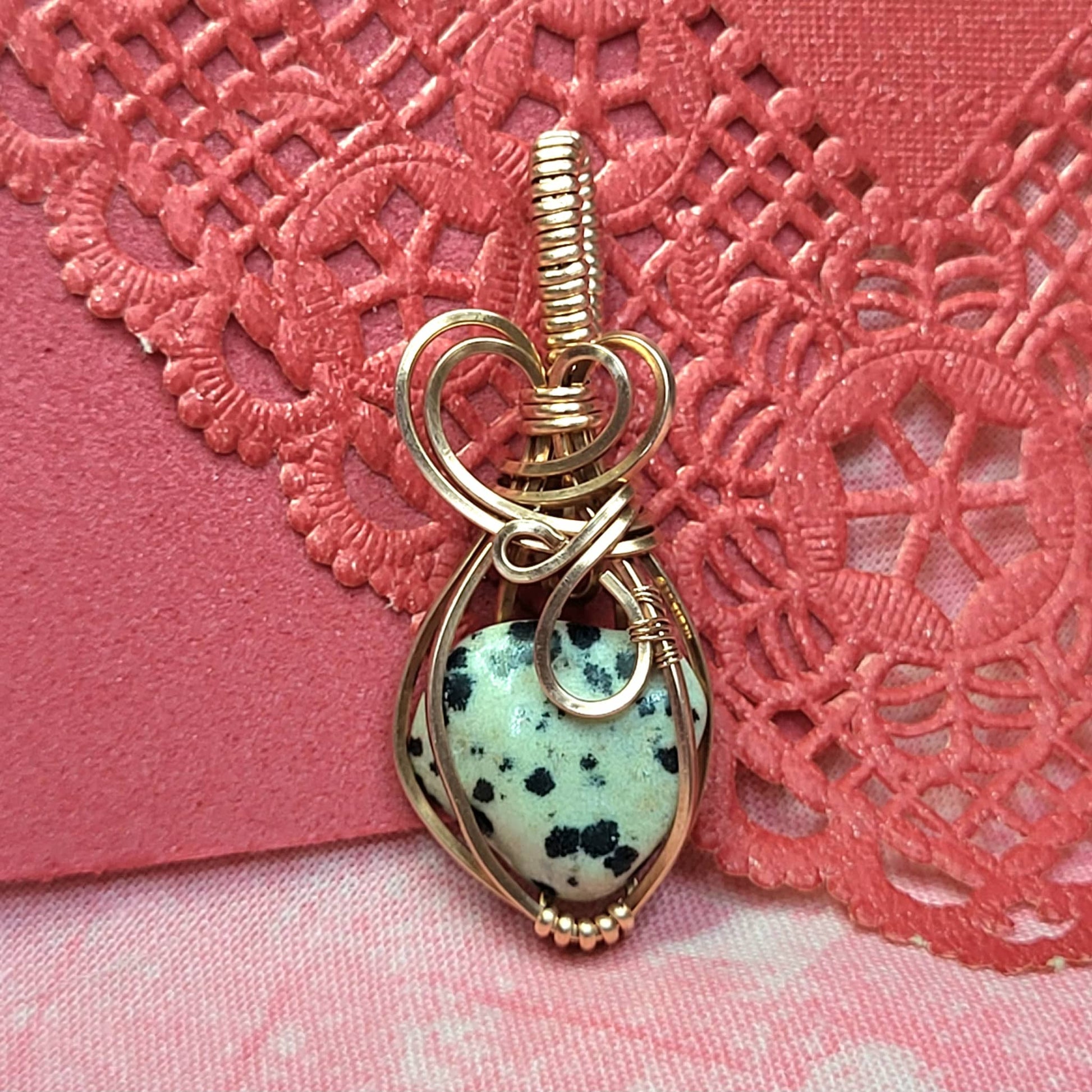 Handcrafted wire-wrapped pendant featuring Dalmation Jasper stone on a decorative background