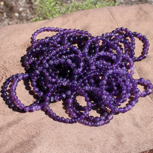 Collection of multiple Deep Purple Amethyst Bracelets on a soft surface displaying their vibrant color