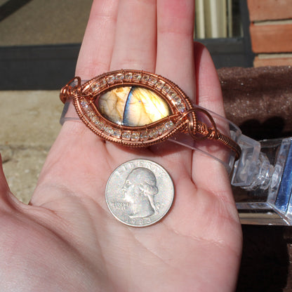 Handcrafted Dragon Eye Labradorite Bracelet with intricate design and colorful stone detail, displayed alongside a quarter
