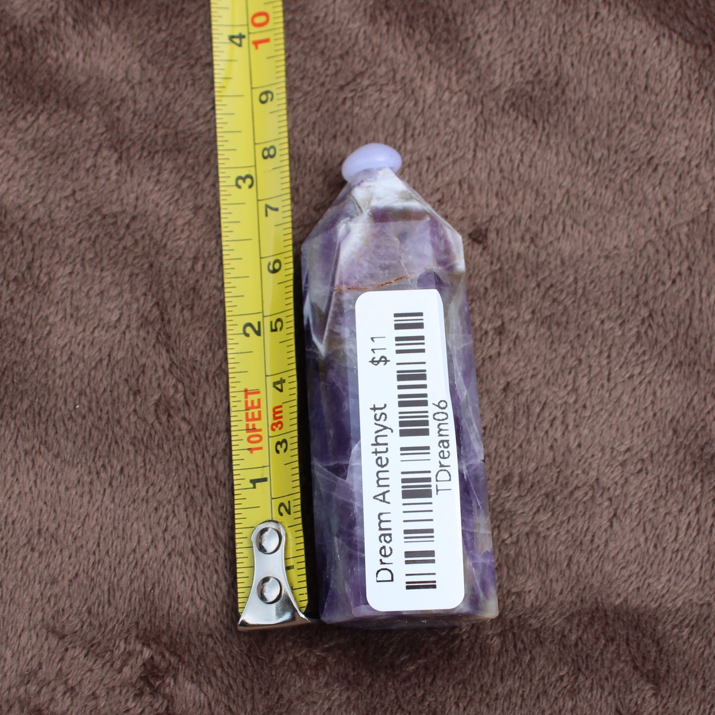 Dream Amethyst Tower crystal by Different Branches LLC shown next to tape measure for size