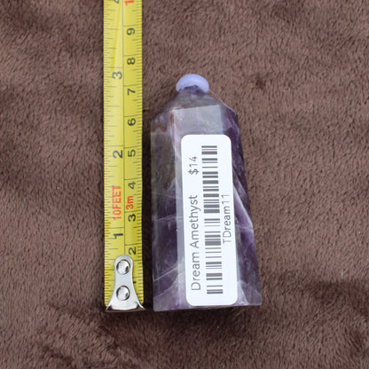 Dream Amethyst Tower crystal with purple and white hues next to measuring tape showing size