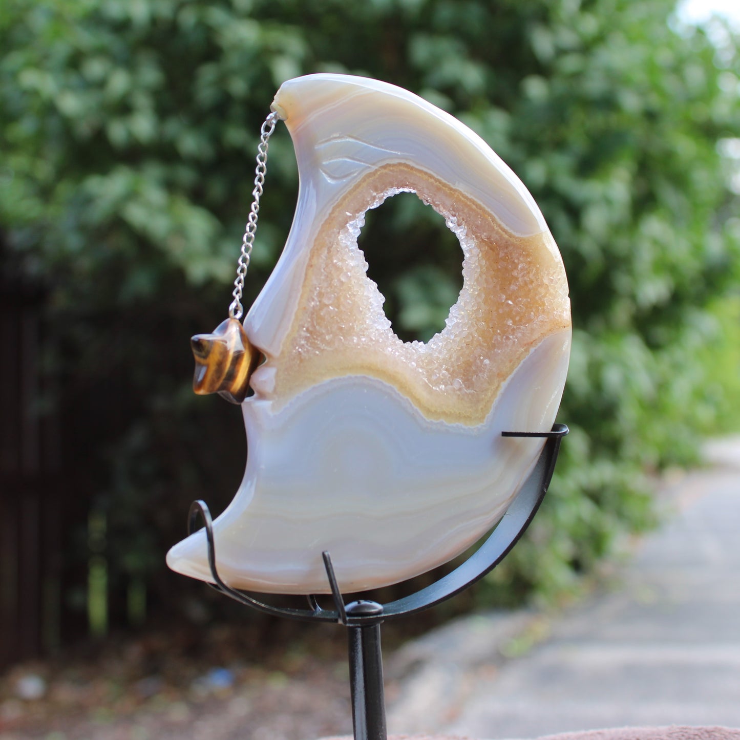 Druzy Agate Moon crystal ornament with star charm on a chain displayed on a black metal stand