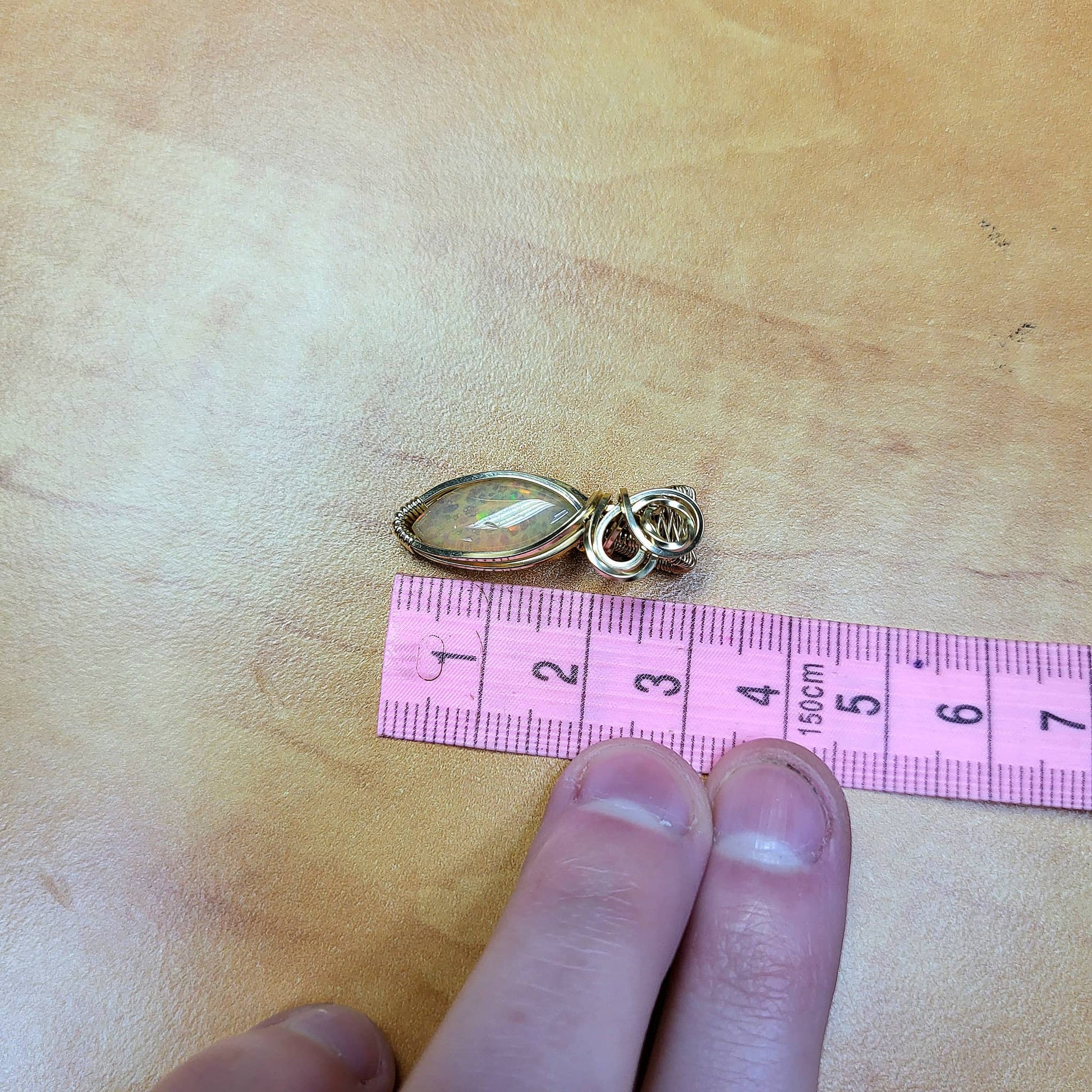 Ethiopian Opal 14k gold-filled pendant displayed next to a ruler for size reference