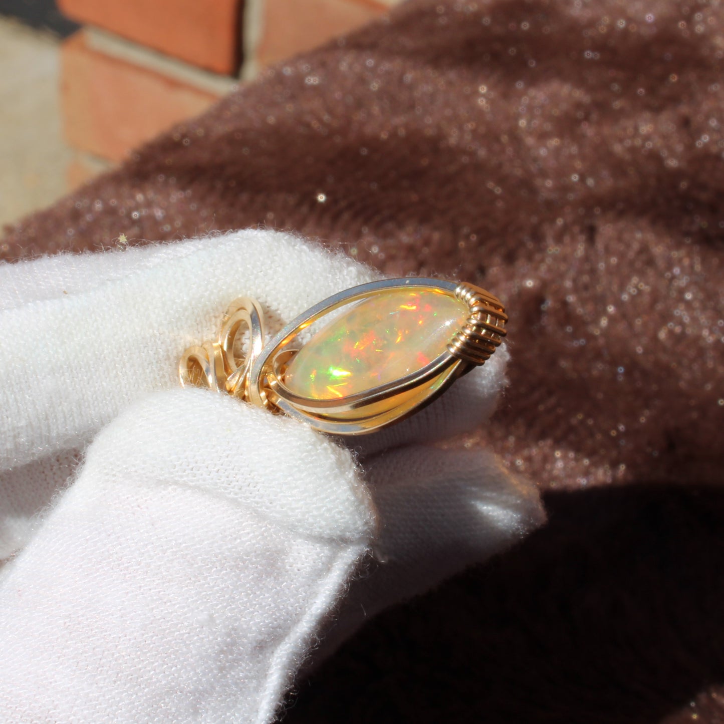 Ethiopian Opal 14k gold-filled pendant displayed with a soft cloth for an elegant showcase