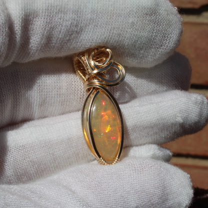 Ethiopian Opal 14k gold-filled pendant displayed on a hand with a white glove for elegant presentation