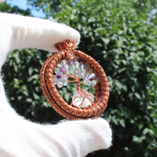 Fluorite tree of life pendant with copper wire and colorful beads displayed outdoors