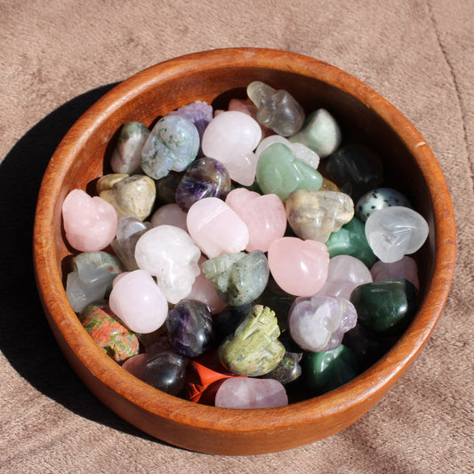 Assorted Gemstone Sugar Skull Carvings in a wooden bowl for decorative use and healing purposes