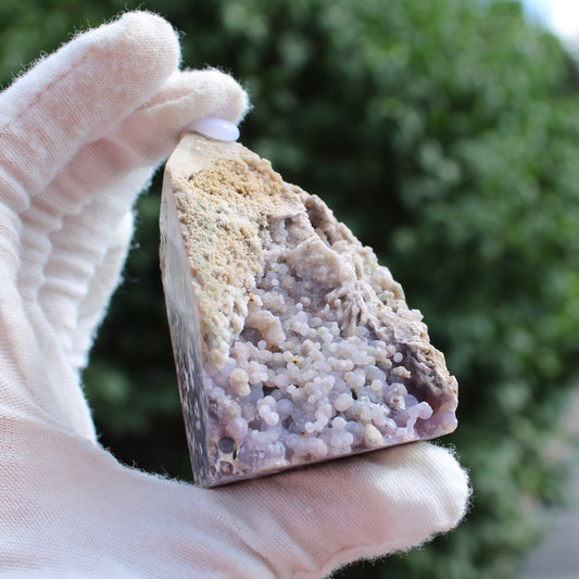 Grape Agate Tower crystal held in gloved hand showing purple botryoidal formations and rough beige surface