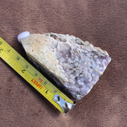 Grape Agate Tower crystal with light purple botryoidal formations next to a measuring tape showing size