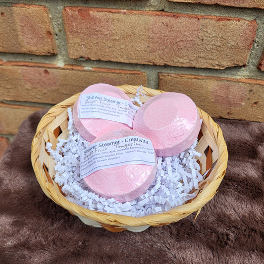 Three pink Grapefruit Tangerine Shower Steamers in a decorative basket with white shred