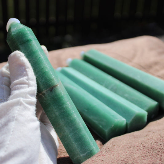 Hand holding a Green Aventurine tower next to several additional green crystal towers