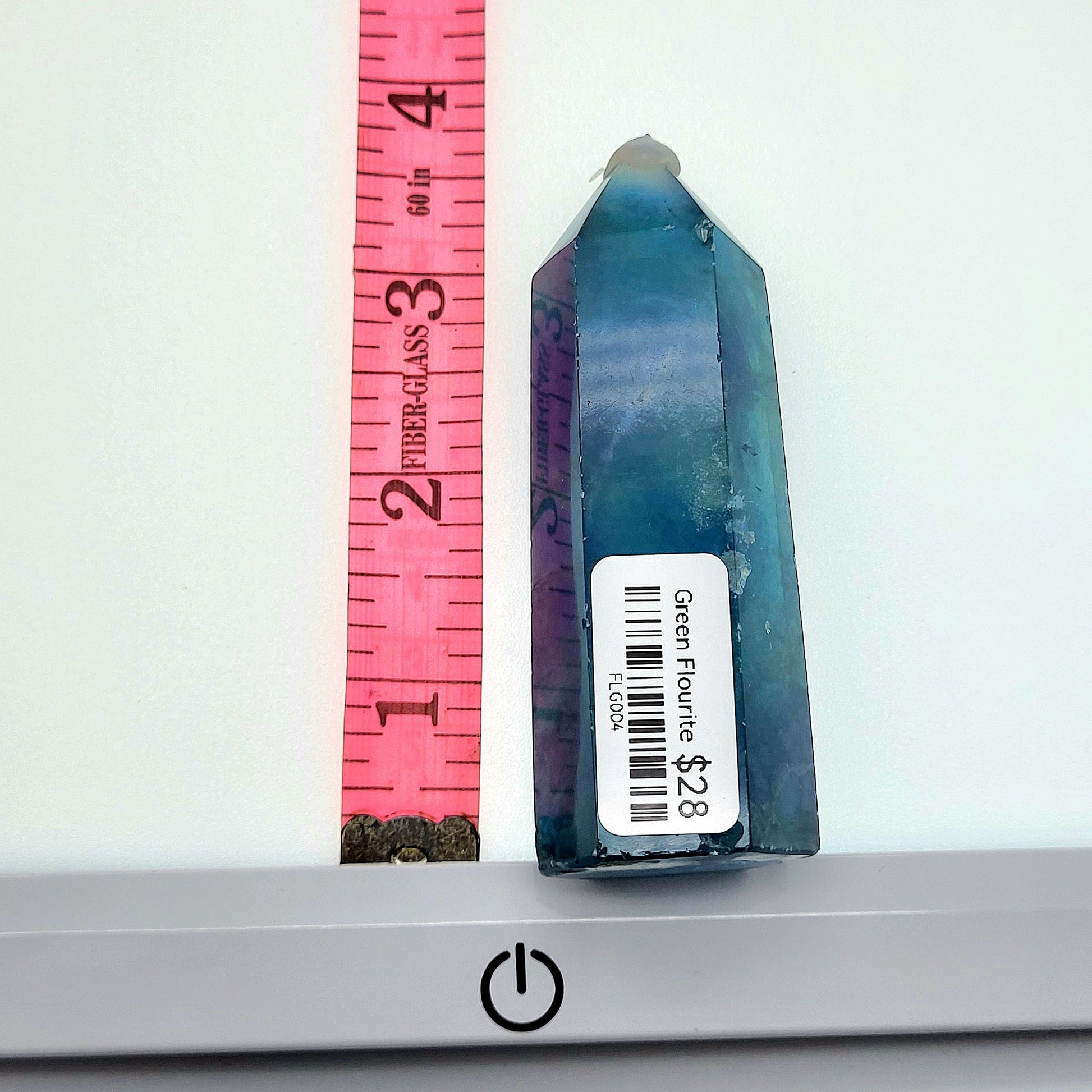 Green fluorite tower displayed with a measurement ruler for size reference and pricing