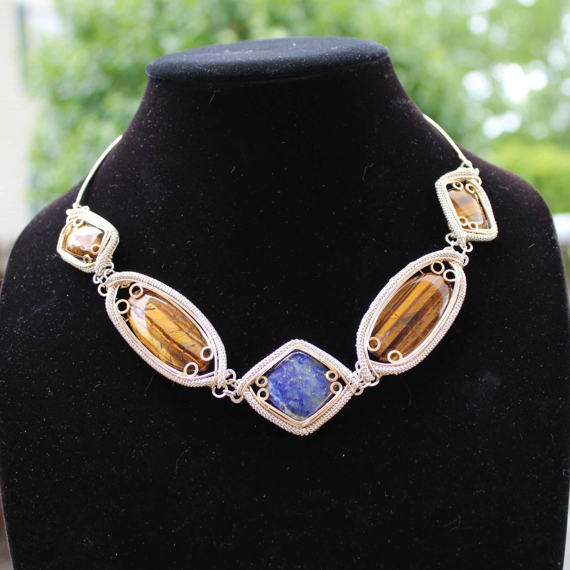 Handcrafted sterling silver necklace featuring colorful gemstones in unique settings