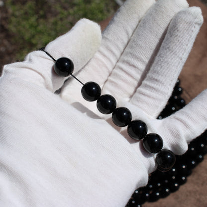 Handmade obsidian bracelet displayed on a gloved hand with polished black beads