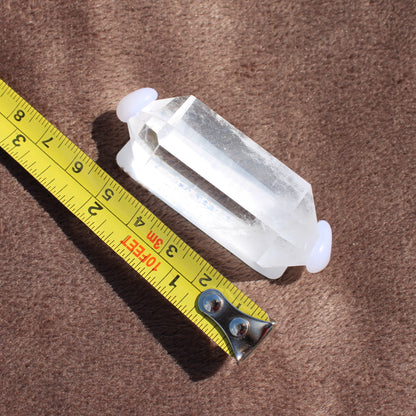High Quality Clear Quartz crystal from Different Branches LLC next to a measuring tape on brown fabric