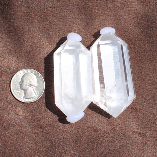High Quality Clear Quartz crystal points next to a US quarter for size comparison on brown fabric