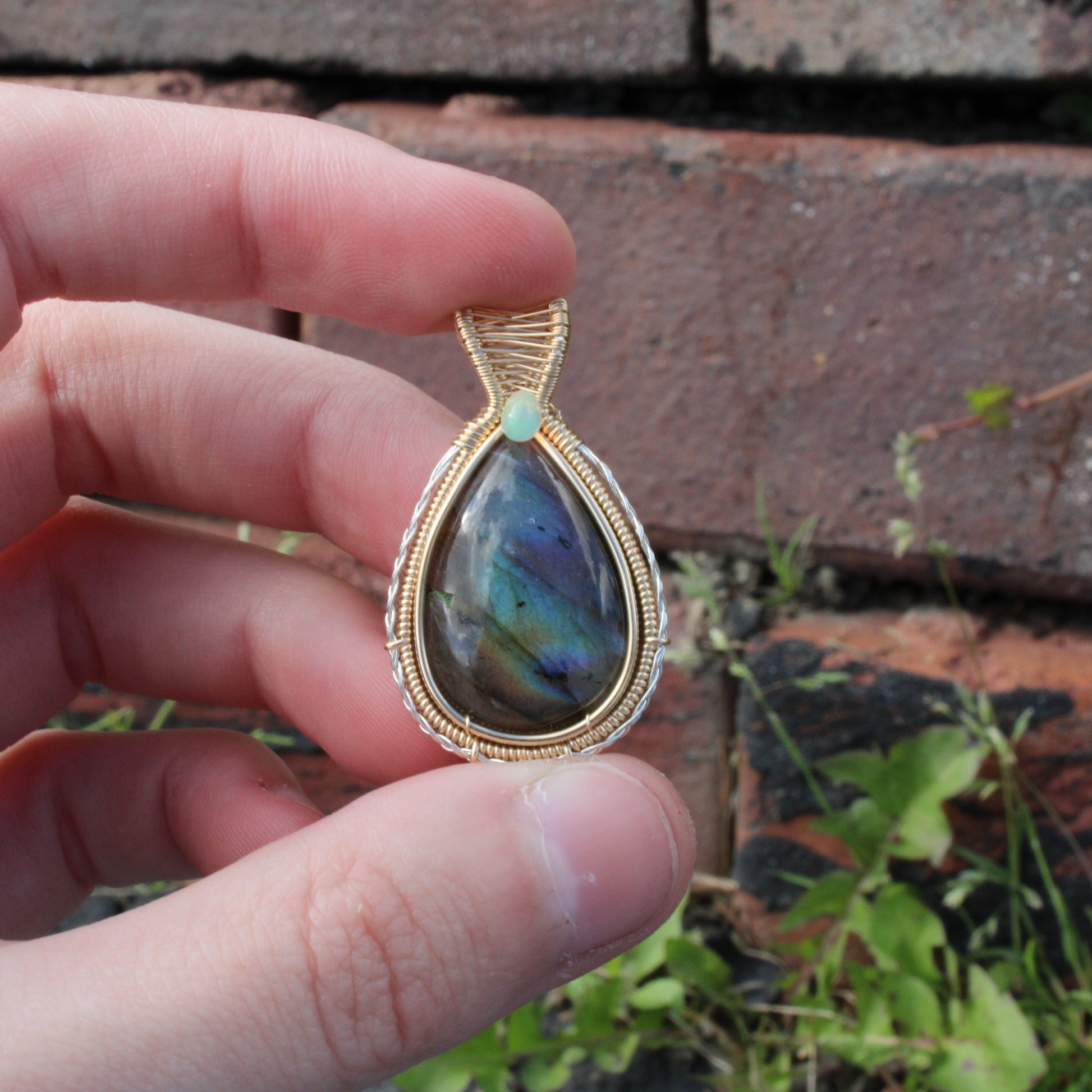 Handcrafted Labradorite 14k Gold Fill and Sterling Pendant held in hand against a brick background