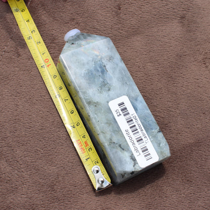 Labradorite Tower crystal from Different Branches LLC shown next to measuring tape on brown fabric