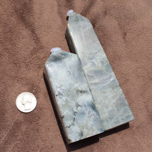 Two polished Labradorite Tower crystals by Different Branches LLC next to a quarter for size comparison
