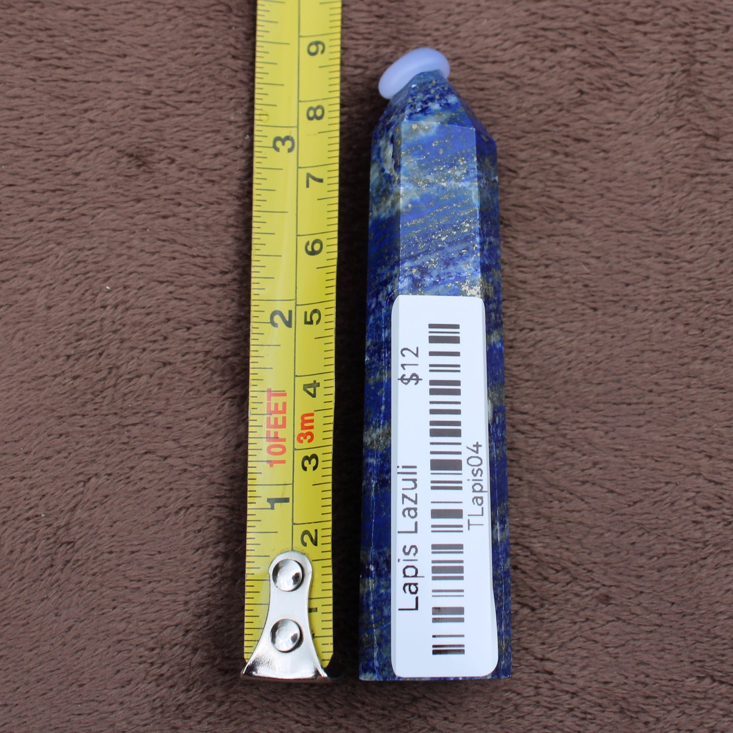 Lapiz Lazuli Tower crystal with blue and gold specks next to a measuring tape showing size