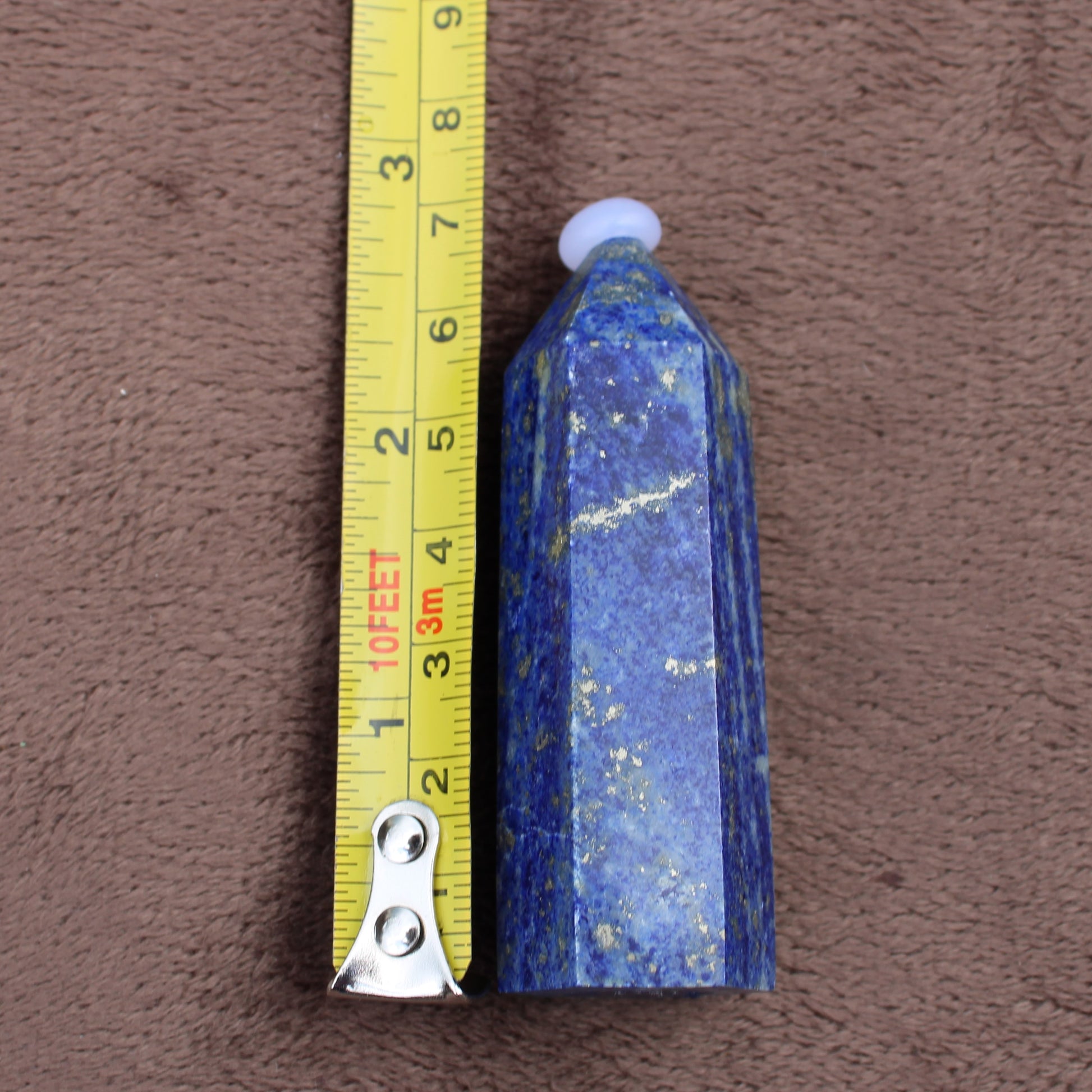Lapiz Lazuli Tower crystal standing next to measuring tape showing size for Different Branches LLC