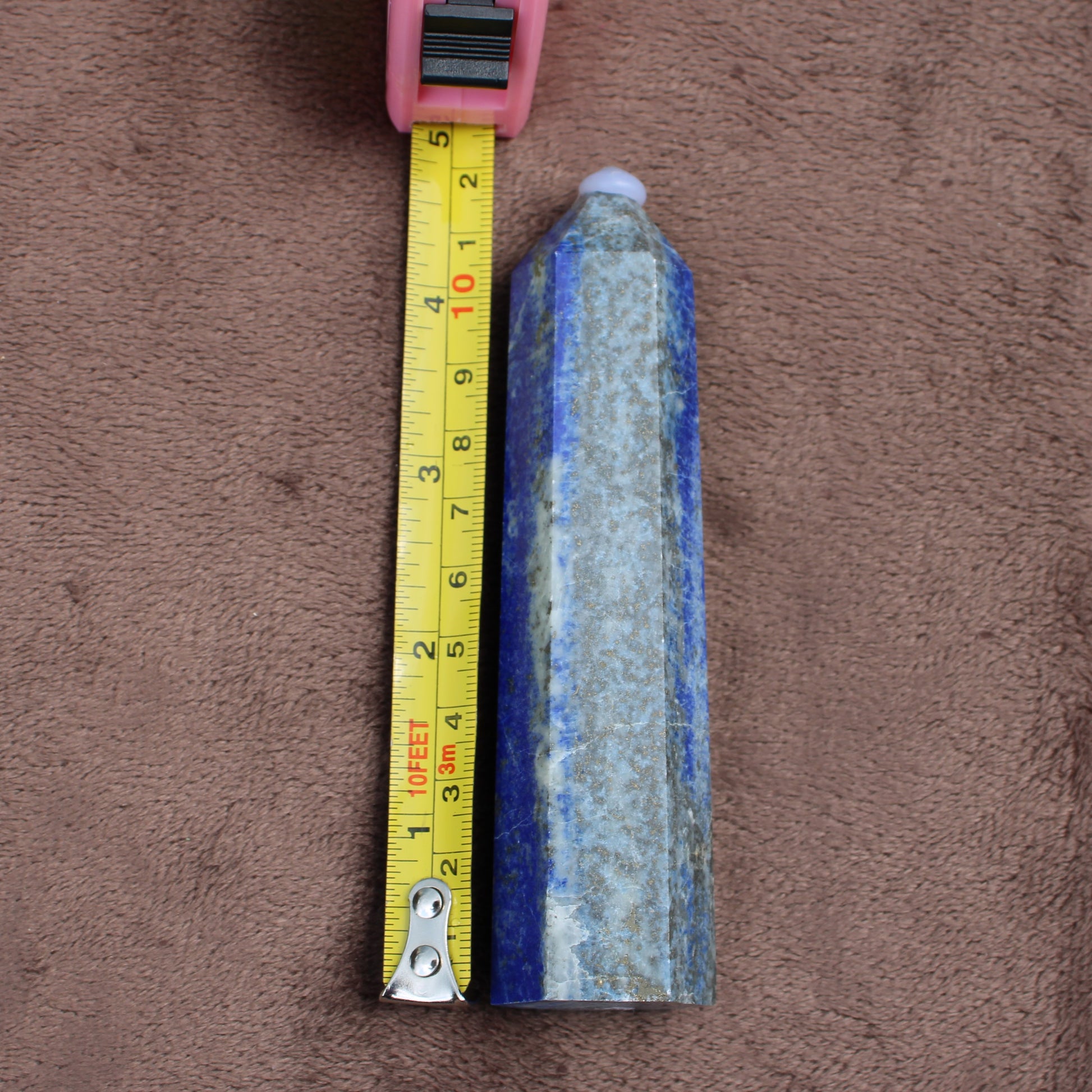 Lapiz Lazuli Tower crystal from Different Branches LLC measuring about 5 inches on a brown background