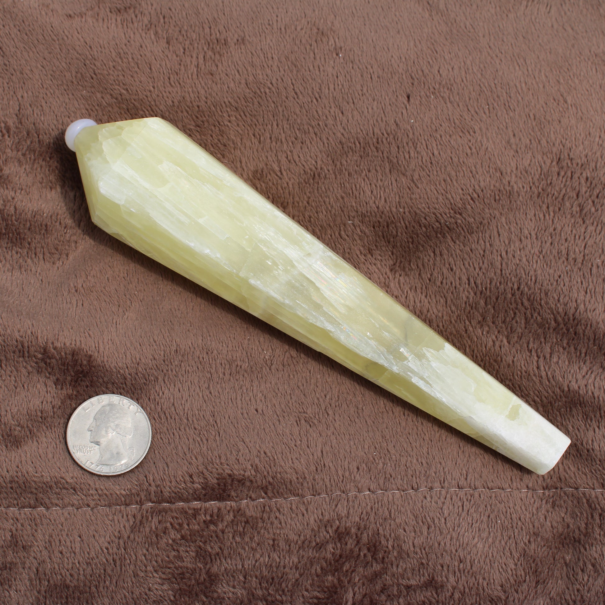 Lemon Quartz Wand crystal by Different Branches LLC displayed next to a quarter for size reference