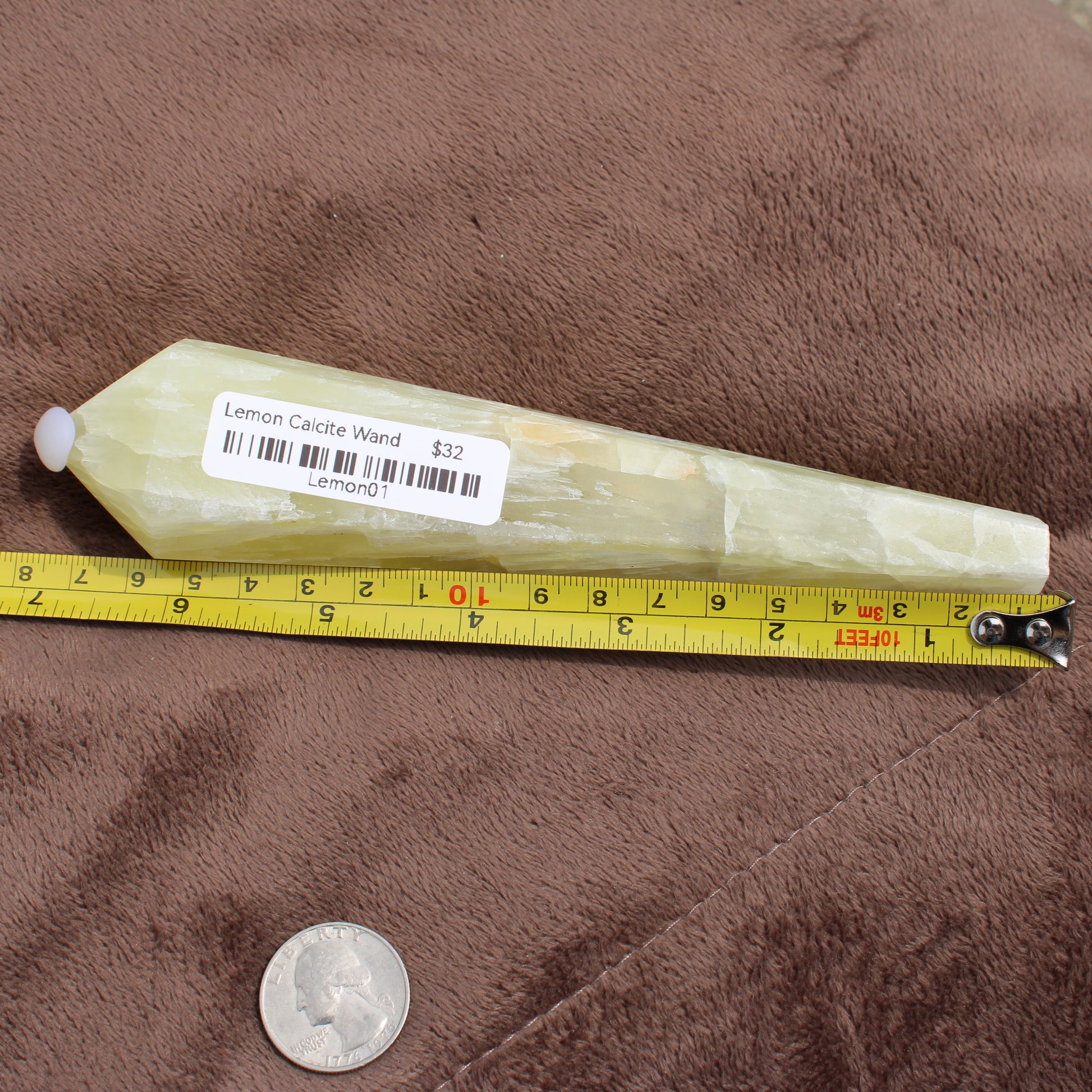 Lemon Quartz Wand crystal from Different Branches LLC placed next to a tape measure and a quarter for size reference