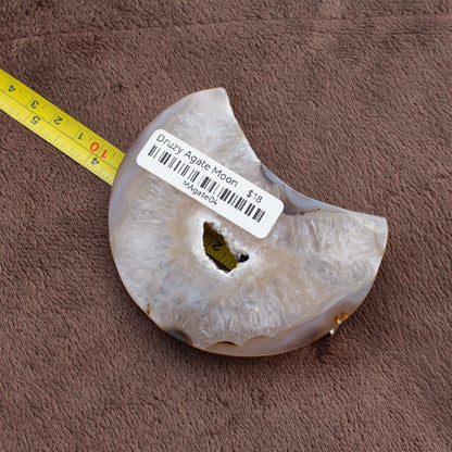 Little Agate Moon crystal with druzy center and ruler for size on brown fabric background
