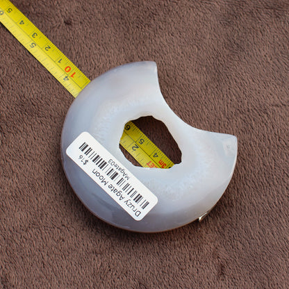 Little Agate Moon crystal from Different Branches LLC shown next to measuring tape on brown fabric