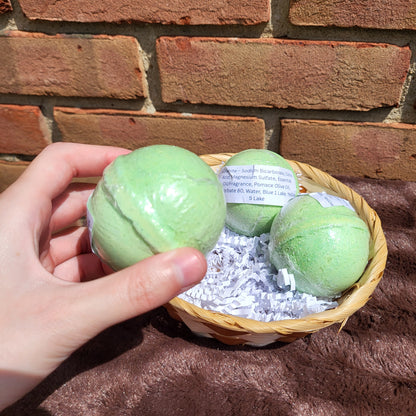 Hand holding a green Malachite Bath Bomb in a basket with three bath bombs for a relaxing soak