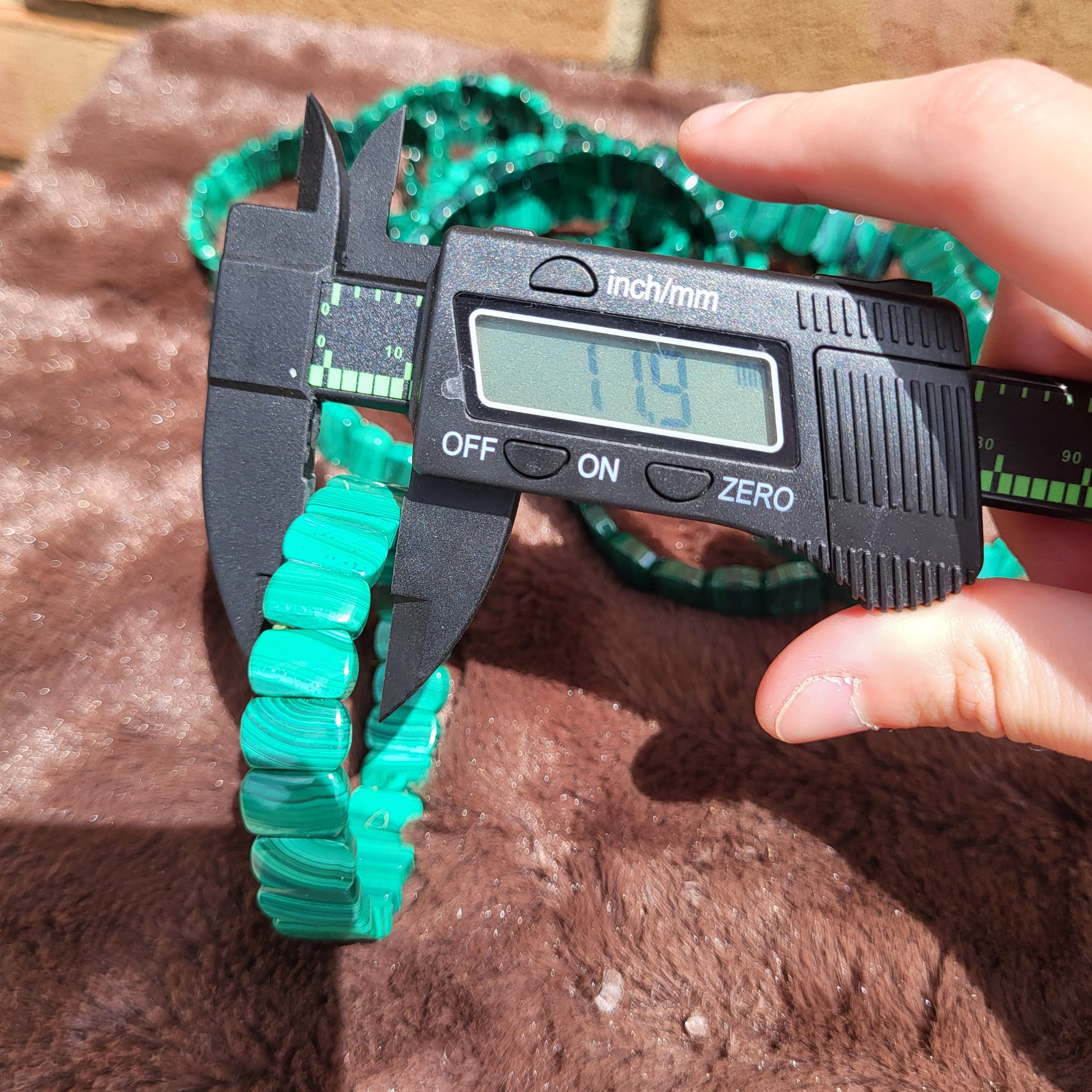 Measuring the diameter of a Malachite Bead bracelet with a digital caliper for precise sizing