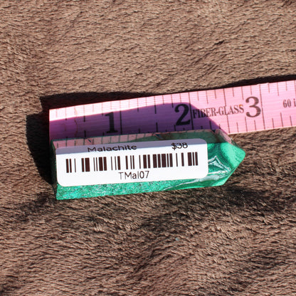 Malachite tower collection displayed on a soft surface with a measuring tape for scale