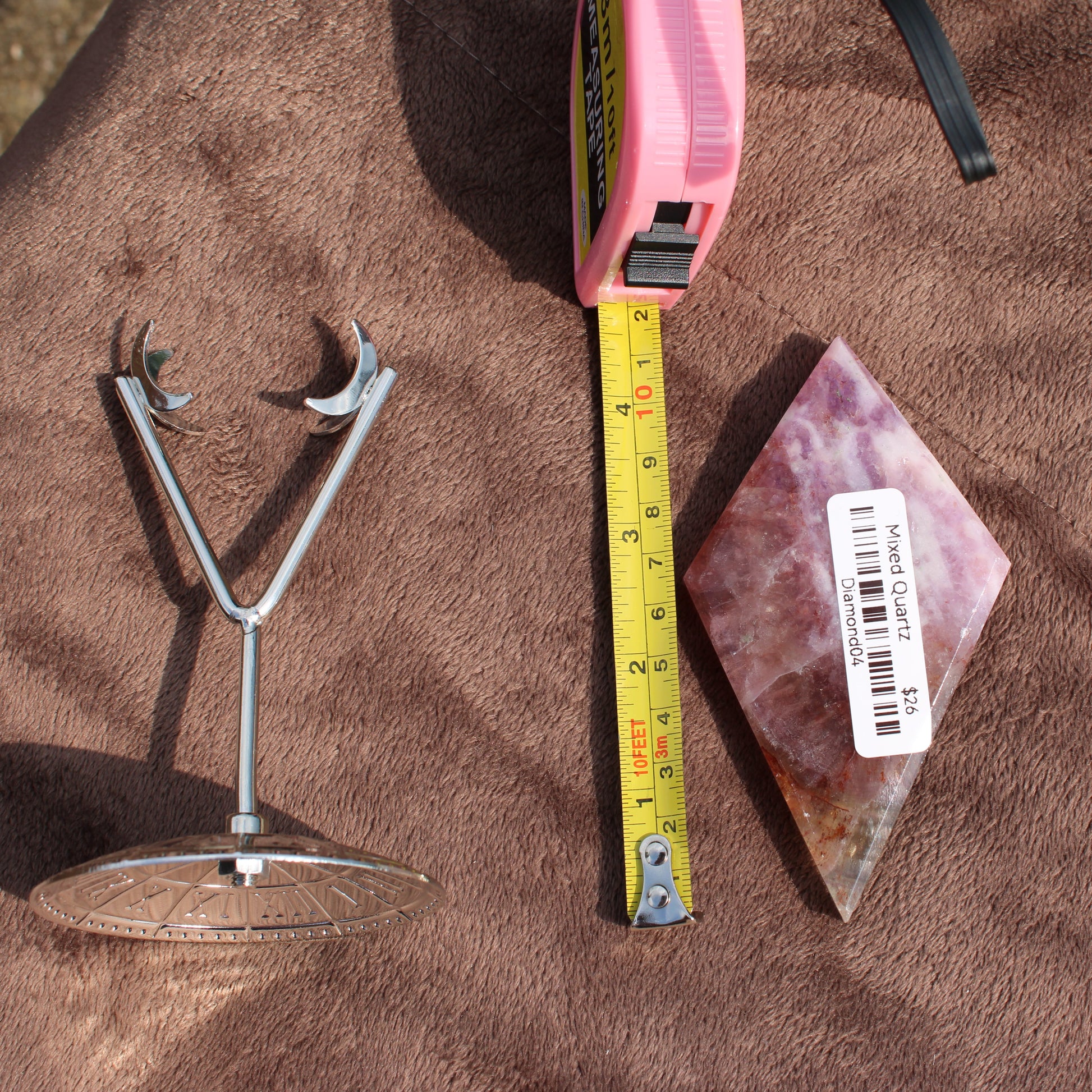 Mixed Quartz Diamond crystal from Different Branches LLC next to a measuring tape and metal stand on brown fabric
