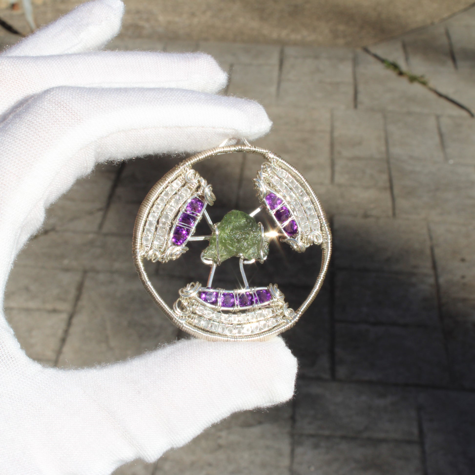 Elegant moldavite amethyst moonstone pendant set in silver with intricate detailing and vibrant colors