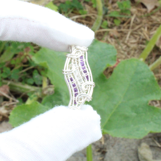 Handcrafted Moonstone, Amethyst, Sterling silver Pendant held between fingers against a green backdrop