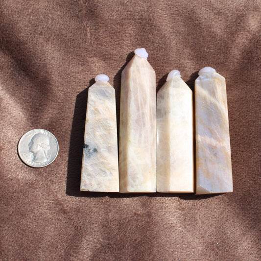 Different Branches LLC Moonstone Tower crystals in various sizes next to a US quarter for scale