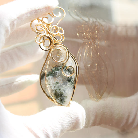 Moss agate pendant 14k gold-filled with intricate wire design held gently in a gloved hand