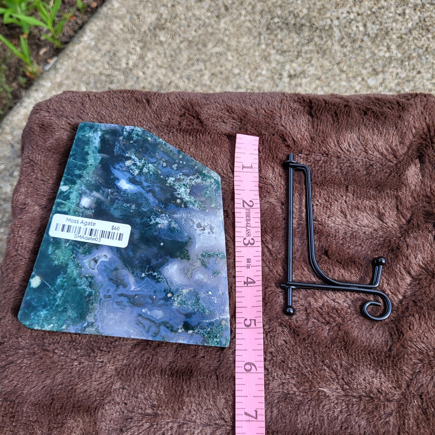 Moss Agate Slab showcasing natural patterns with a measuring tape and display holder for crystal enthusiasts